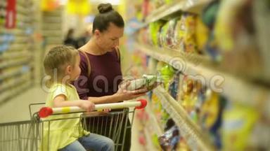 母亲和女儿在<strong>超市</strong>购物。 他们正在买早餐片。 一个女儿坐在<strong>超市</strong>